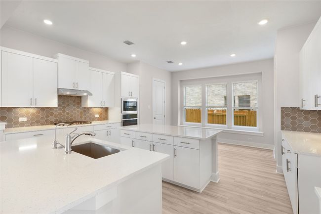 Kitchen featuring a sink, stainless steel oven, a center island, under cabinet range hood, and gas cooktop | Image 8