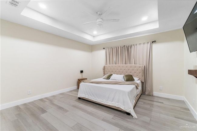 Bedroom featuring a raised ceiling, ceiling fan, and light hardwood / wood-style floors | Image 12