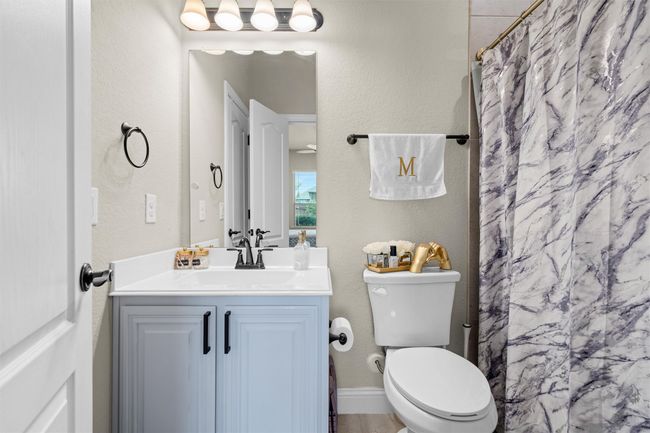 Bathroom with vanity, curtained shower, and a textured wall | Image 13