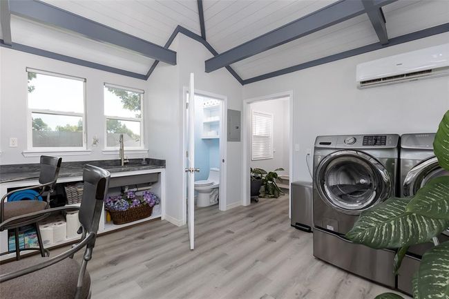 Laundry area with wooden ceiling, light wood-type flooring, washer and dryer, and a wall mounted air conditioner | Image 31