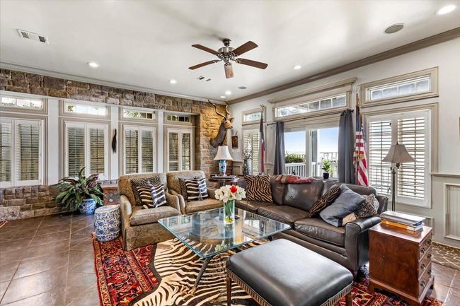 Downstairs living area opens onto a full length porch looking onto the bay. Storm proof casement windows with plantation shutters allow you and your guests to enjoy the beautiful gulf views no matter what the weather is. | Image 10