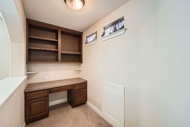 Unfurnished office featuring baseboards, light colored carpet, and built in desk | Image 32