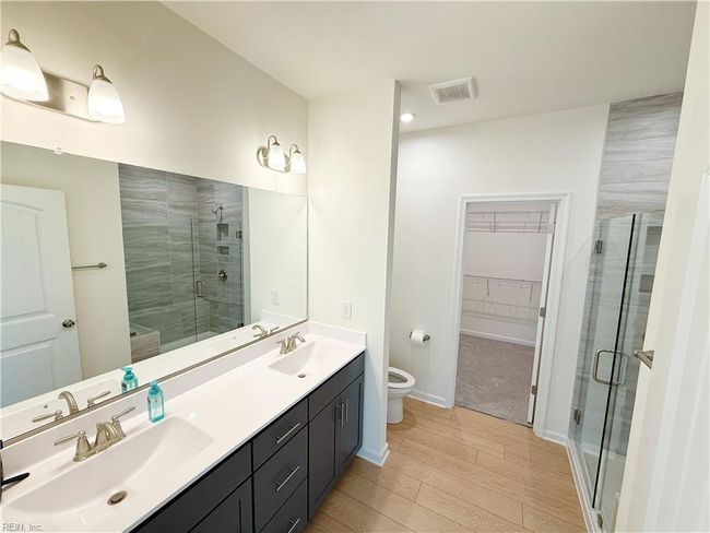 A first-floor primary suite features a walk-in closet and an ensuite bath with double vanity. | Image 8