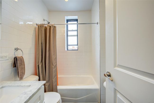 Bathroom with tile walls, toilet, vanity, and shower / bath combination with curtain | Image 9