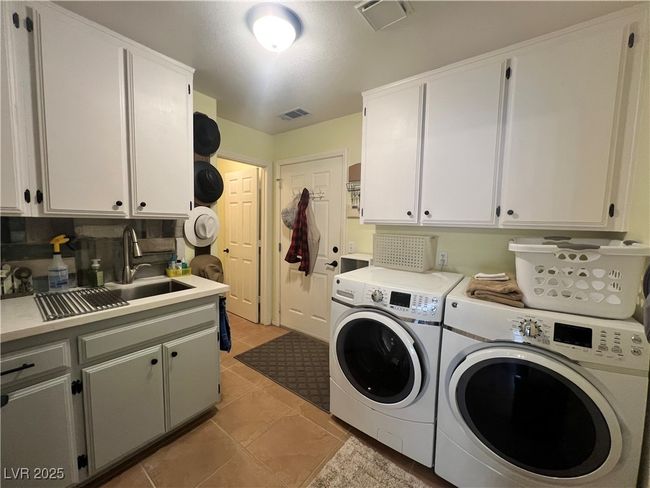 Laundry area featuring cabinet space, washing machine and clothes dryer, and light tile patterned floors | Image 21