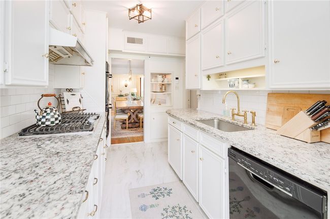 Kitchen with black dishwasher, stainless steel gas stovetop, a sink, open shelves, and backsplash | Image 10