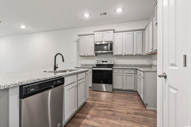 Kitchen featuring appliances with stainless steel finishes, dark wood-style flooring, gray cabinetry, and recessed lighting | Image 32