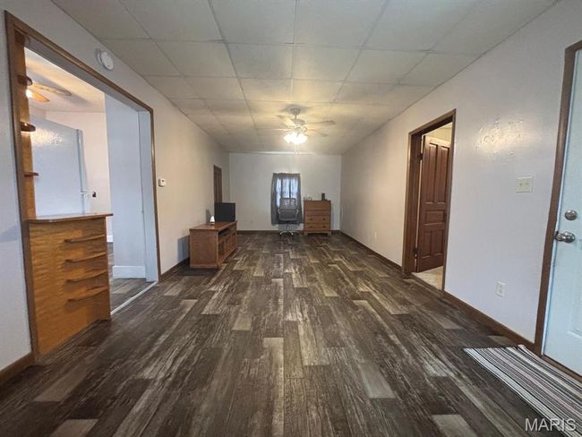 Unfurnished living room with dark wood-style floors, a ceiling fan, and a drop ceiling | Image 16