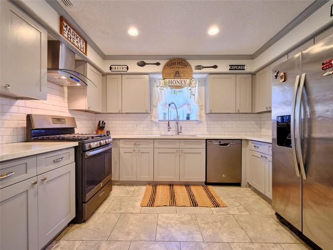 The kitchen features updated countertops and sink, painted cabinets, and stainless steel appliances. | Image 10