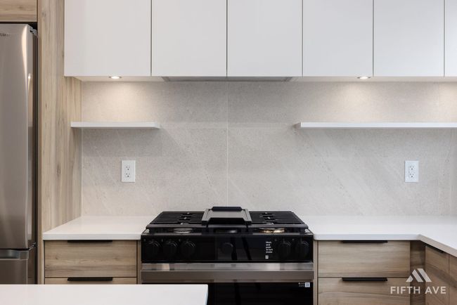Kitchen featuring modern cabinets, range with gas cooktop, freestanding refrigerator, and white cabinetry | Image 19