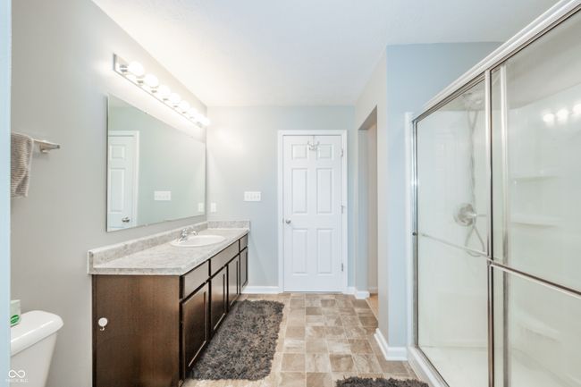 bathroom with a stall shower, vanity, toilet, baseboards, and stone finish floors | Image 34