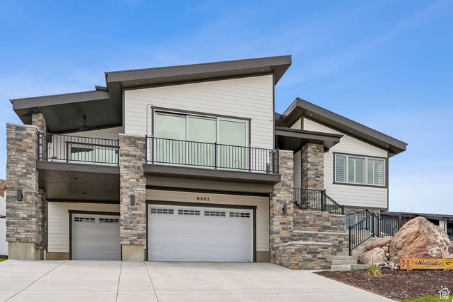 Contemporary home with stone siding, a balcony, driveway, and an attached garage | Image 4
