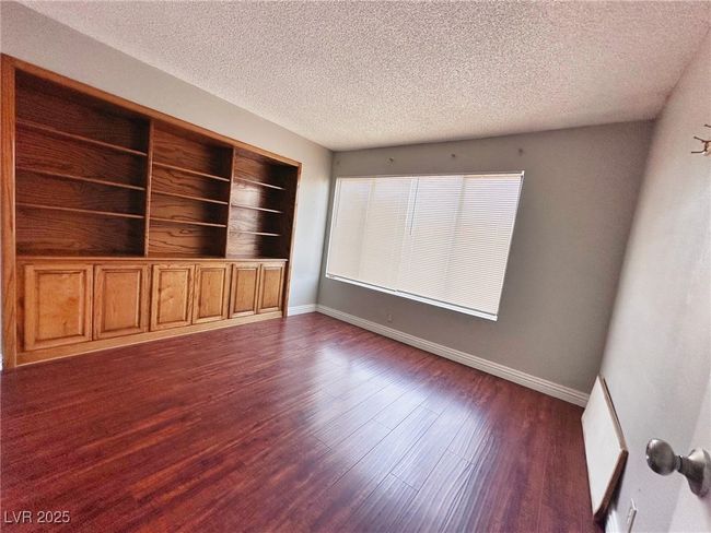 Spare room featuring a textured ceiling, dark wood-style floors, and baseboards | Image 7