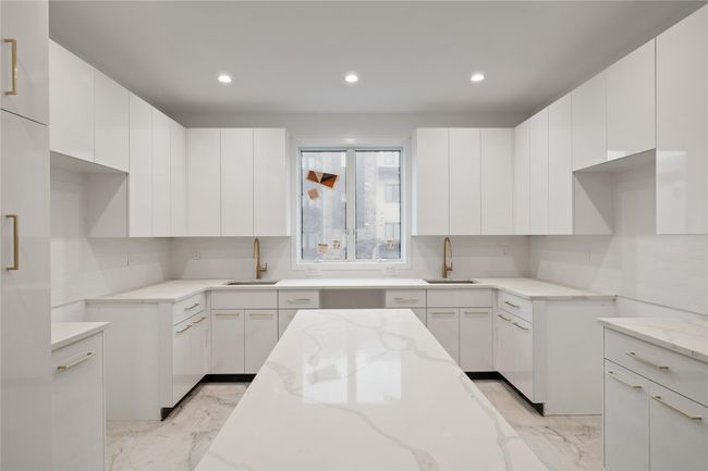 Kitchen with a sink, light stone counters, light marble finish floors, white cabinets, and recessed lighting | Image 11