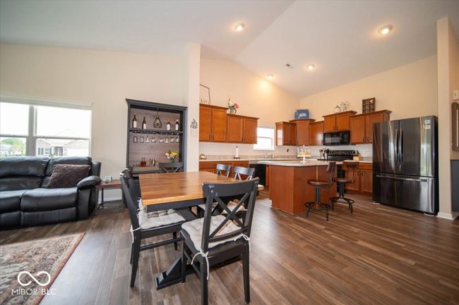 dining space featuring dark vinyl flooring with wood appearance and high vaulted ceiling | Image 16