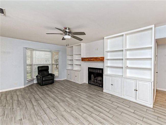 Unfurnished living room with ceiling fan, light wood-type flooring, and a fireplace | Image 27