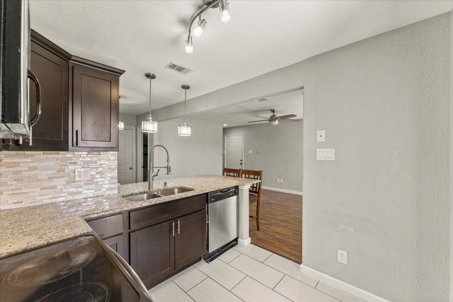 Kitchen featuring dark brown cabinetry, appliances with stainless steel finishes, a ceiling fan, a peninsula, and light stone counters | Image 17