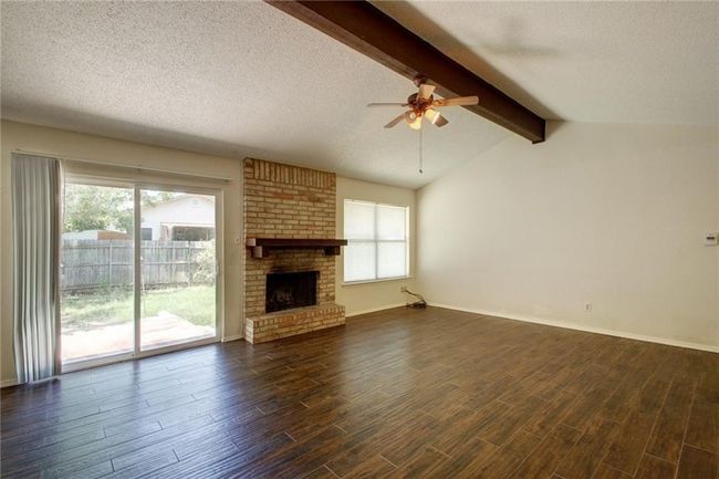 Unfurnished living room with dark finished flooring, ceiling fan, a textured ceiling, and a healthy amount of sunlight | Image 8