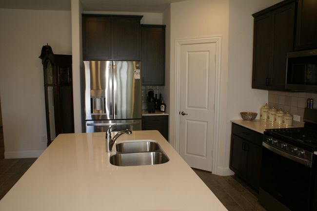 Kitchen with island, a sink, tasteful backsplash, dark wood-style floors, appliances with stainless steel finishes, and light countertops | Image 15