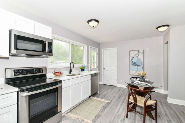 kitchen with appliances with stainless steel finishes, a sink, light countertops, and white cabinets | Image 11