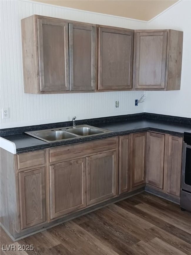 Kitchen featuring a sink, stove, dark wood-type flooring, and dark countertops | Image 18