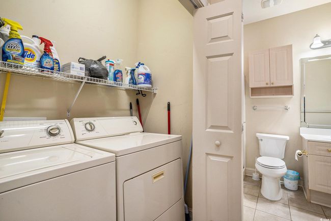 Clothes washing area featuring light tile patterned floors and washing machine and dryer | Image 14