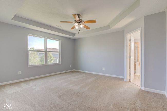 empty room with a raised ceiling, ceiling fan, and light carpet | Image 31