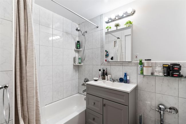 Bathroom featuring shower / tub combo, vanity, and tile walls | Image 8