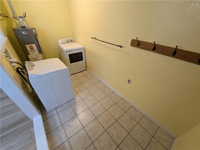 Laundry area with water heater, light tile patterned floors, baseboards, and washing machine and dryer | Image 25