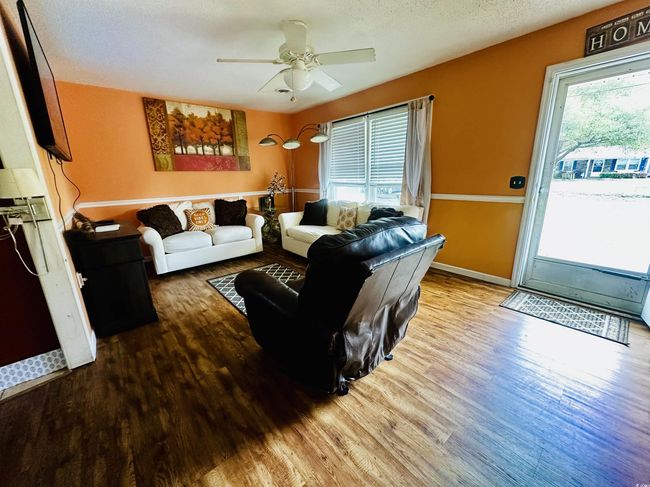 Living area featuring a textured ceiling, baseboards, a ceiling fan, and wood finished floors | Image 4