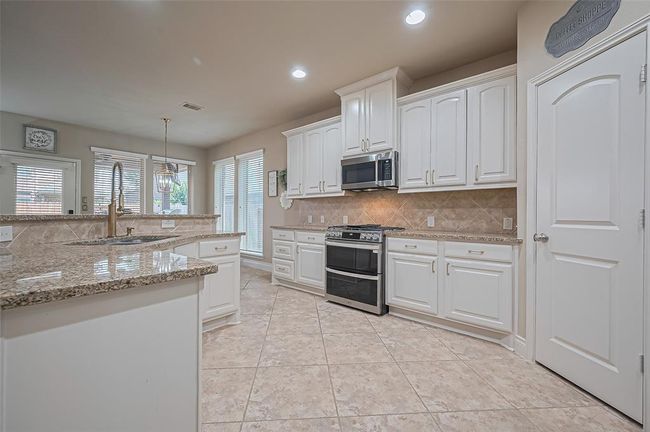 Bright and inviting, this beautifully updated kitchen features granite counters and newly refinished cabinetry in a soft, modern tone—elevated with gleaming gold hardware. | Image 9
