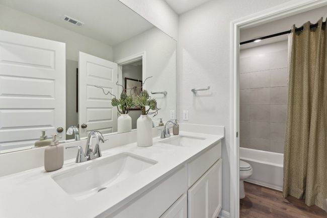 Full bath with toilet, wood finished floors, shower / bath combination with curtain, and double vanity | Image 12