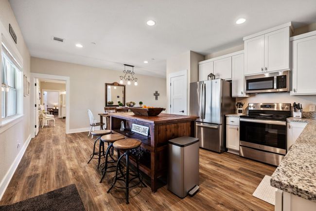 Kitchen with appliances with stainless steel finishes, dark wood finished floors, white cabinetry, a kitchen island, and recessed lighting | Image 31