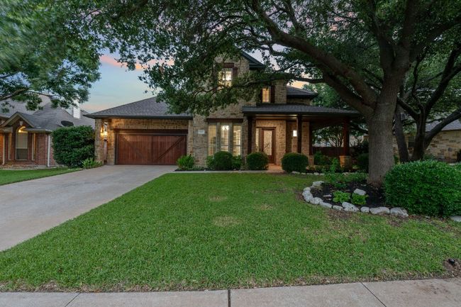 View of front of house with a front lawn, an attached garage, driveway, roof with shingles, and brick siding | Image 24