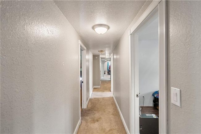 Hallway featuring light carpet and a textured ceiling | Image 46