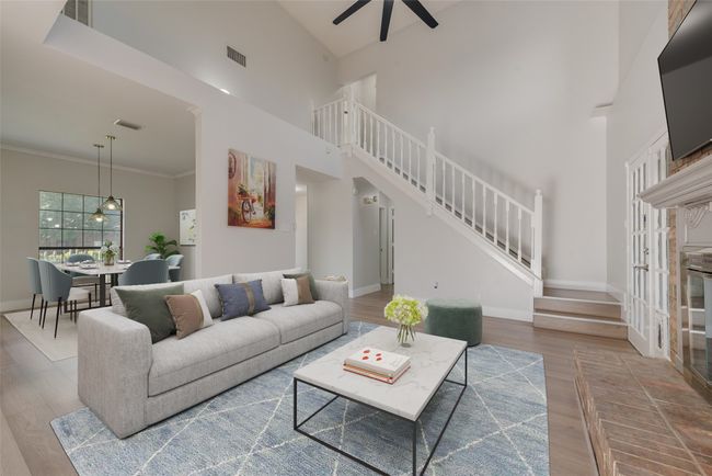 Living area featuring stairway, a ceiling fan, wood finished floors, and a towering ceiling | Image 4