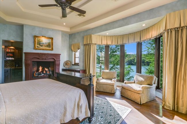 Bedroom featuring recessed lighting, a raised ceiling, visible vents, a warm lit fireplace, and wood finished floors | Image 28
