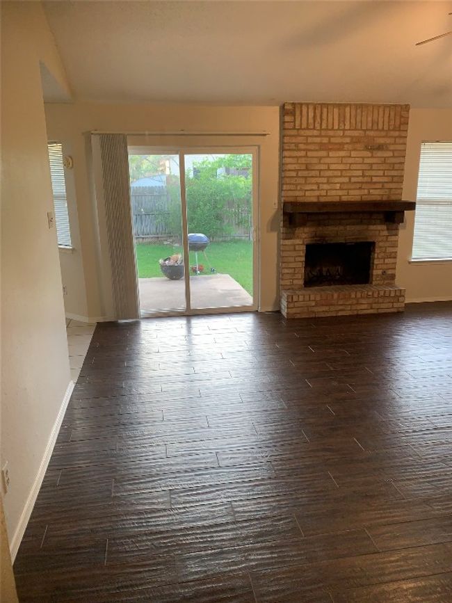 Unfurnished living room with baseboards, finished floors, and a fireplace | Image 11