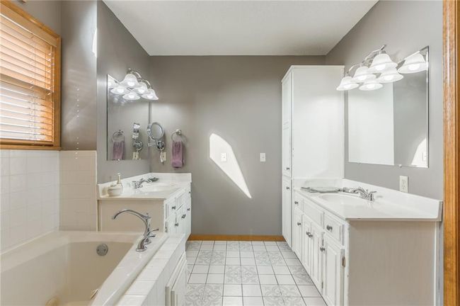 Full bath featuring a garden tub, baseboards, two vanities, and a sink | Image 37