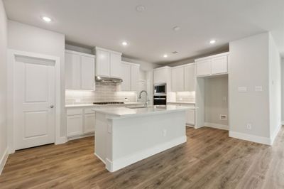 Kitchen featuring appliances with stainless steel finishes, a center island with sink, white cabinets, and light hardwood / wood-style floors | Image 3