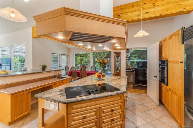 Kitchen with black appliances, light tile patterned floors, a kitchen island, and plenty of natural light | Image 20