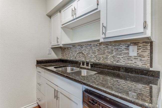 Kitchen with a sink, tasteful backsplash, white cabinetry, dark stone countertops, and dishwasher | Image 7