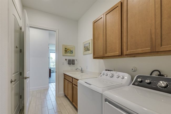 Laundry area featuring cabinet space, washing machine and clothes dryer, and wood tiled floors | Image 18