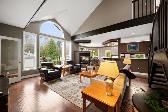 Living room featuring baseboards, wood finished floors, a multi sided fireplace, and high vaulted ceiling | Image 10