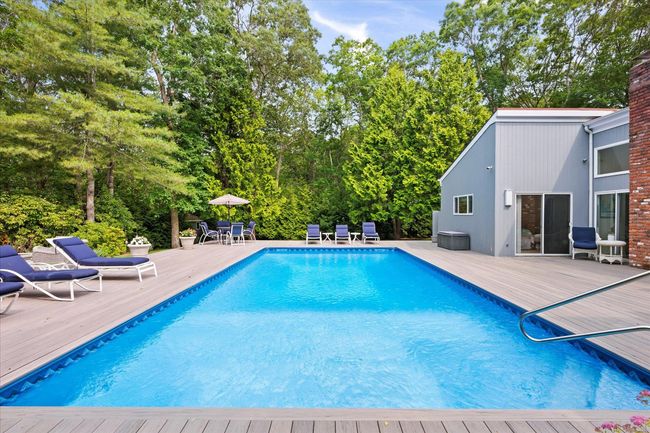 Swimming pool with a deck and view of wooded area | Image 26