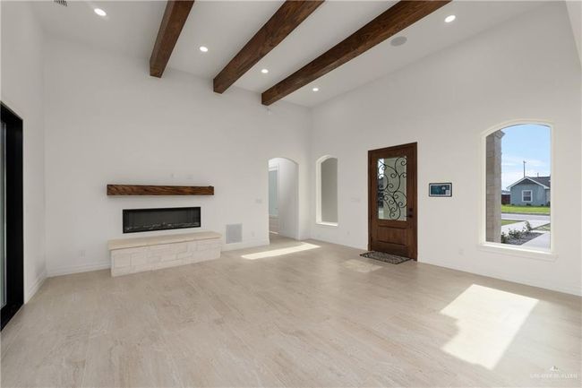 Stunning, light-filled living room with soaring vaulted ceilings and rich wood beam accents that add rustic elegance. | Image 5