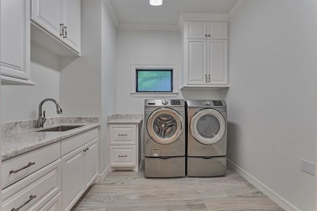The laundry room is both sleek and stylish, offering ample storage with upper cabinets and drawers, plus plumbing in place for a future refrigerator, making it as functional as it is polished. | Image 32