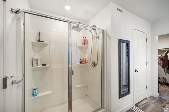 Bathroom with a shower stall, wood finished floors, a spacious closet, baseboards, and recessed lighting | Image 21