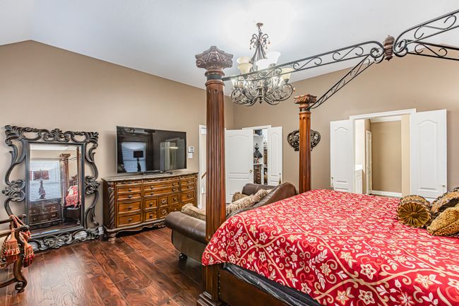 Bedroom with lofted ceiling, dark wood finished floors, a chandelier, and ornate columns | Image 20