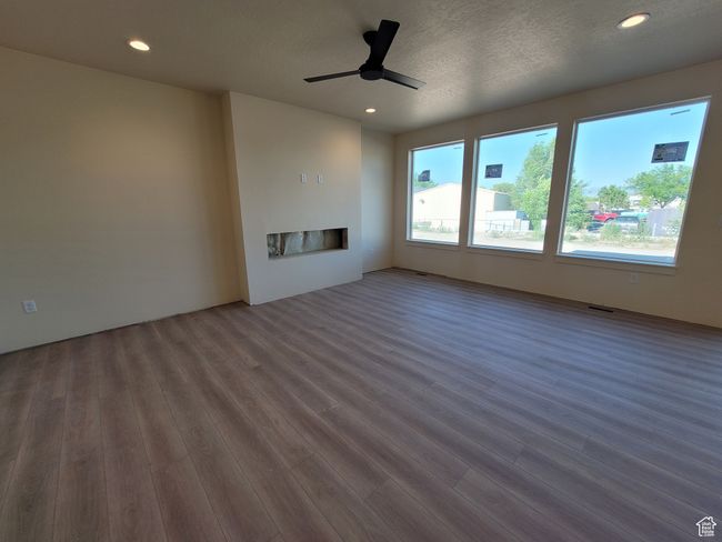 The open concept Family Room has a wall of windows for tons of natural light, a sliding glass door out to a 12x12 patio, and an electric fireplace. | Image 4